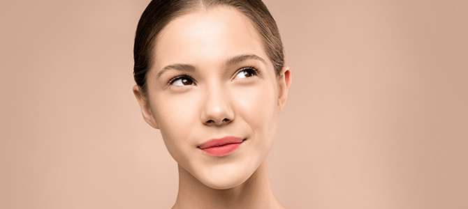Glowing Skin Article - 01 woman with glowing skin looking off to the side with a tan background